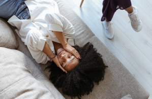 Stressed woman lying on couch holds face in hands