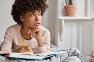 Woman looking out the window and writing in her journal