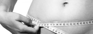 Woman measuring her waist with a soft tape measure.