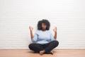 Woman in a blue sweater sitting on the floor and meditating