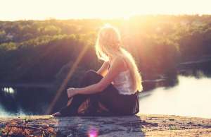 woman-sitting-on-brown-surface-staring-at-water