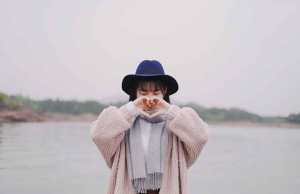 woman holding hand heart by water