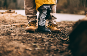 adult and child standing on soil in boots