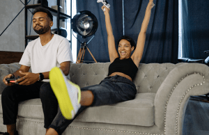 man and woman playing video game while sitting on sofa