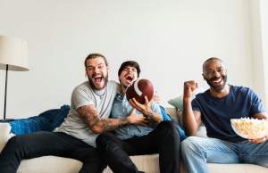 Men watching sports together while eating popcorn