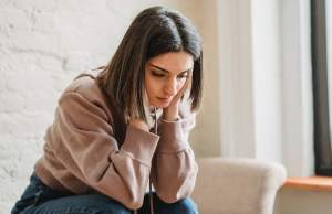 Sad woman sitting on couch in pink sweater