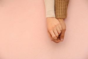 People holding hands against pink background.