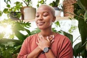 Woman touching her hands to her heart with plants around her